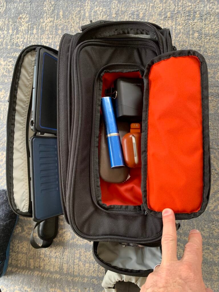A top down view of the Aerocoast Pro Crew I showing the bright orange top pocket containing glasses, torches, and earbuds.